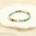 Detail of colorful Tila tile bead bracelet with gold accents on a white shell plate - Light Blue & Green Set