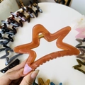 Close-up of caramel pentagram hair claw clip with transparent acrylic and metal spring - 11cm / Translucent Dark Orange