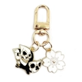 Detail of gold keychain with black and white skull charm and white sakura flower pendant - Flying Butterfly + White Cherry Blossom