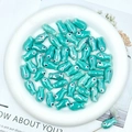 Detail of glossy teal ceramic fish beads for handmade DIY jewelry in a white porcelain bowl - Blue Howlite