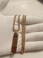 Detailed view of a gold-plated 3D rectangular pendant on a box chain held in hands - Gold Necklace