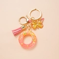 Close-up of pink resin letter O keychain with butterfly charm and soft tassel detail - Letter O