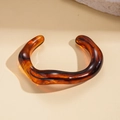 Macro detail of amber acrylic wavy bangle showing glossy texture and organic shape - Amber