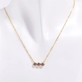Détail du collier doré avec trois pierres violettes serties sur une fine chaîne en or - Février