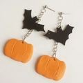Dettaglio di orecchini di Halloween con pipistrelli neri e zucche arancioni su sfondo bianco - Pipistrello e zucca
