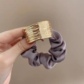 Dettaglio di elastico in raso viola con fibbia in metallo dorato testurizzato in mano - Scrunchie / Viola