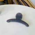 Detailed close-up of a dark grey translucent curved hair claw clip on a white surface - Light Silver Grey