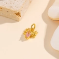 Gros plan du pendentif araignée dorée avec gemme rose sur pierre naturelle et coquillage - Rose