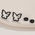 Detail of hollow butterfly earrings in black finish on a beige textured platform - 670 Hollow Butterfly / Black