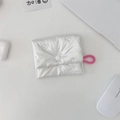 Dettaglio mini borsa argento con fiocco goffrato e cordino rosa su una scrivania bianca - Custodia Quadrata con Bottone a Pressione / Beige