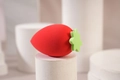 Strawberry-shaped makeup sponge in red with green leaf detail on a display stand - Bright Red Strawberry