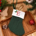 Green cable knit Christmas stocking with red embroidered letter E and holly leaf - Letter E