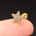 Makroaufnahme eines winzigen goldenen Stern-Ohrsteckers mit Zirkonia auf der Fingerspitze - Pentagramme / Gold (Stern)