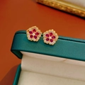 Détail de boucles d'oreilles fleurs dorées avec zircons rouges et blancs sur boîte - Tige d'oreille en argent - Or - Rose