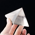 Transparent white crystal pyramid energy stone held in hand with black background - 6.5cm
