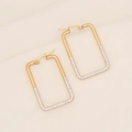 Macro shot of gold geometric earrings featuring sparkling white zircon stones on textured fabric - Rectangle