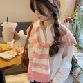 Detail of pink and white striped knit shawl accessory on a model in a cafe setting - Pink