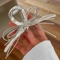 Detailaufnahme einer silbernen Haarklammer in Schleifenform mit Herzanhänger aus Metall - Groß / Silber