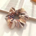 Plaid checkered scrunchie in beige, orange, and blue fabric on an open book - JK Yamabuki