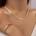 Close-up of golden flat snake bone chain necklace and bracelet set on a female model - Gold Jewelry Set
