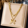 Macro detail of gold layered necklace with bow pendant on beige jewelry stand - Double Layer Chain with 3D Bowknot Style (N4110)