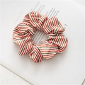 Detail of red, green and white striped festive scrunchie on a magazine page background - Striped Velvet