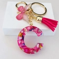 Dettaglio macro portachiavi lettera C in resina con nappe rosa e accenti dorati - Clip Nappa Farfalla Rosso Rosa / Lettera C