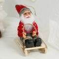 Santa Claus plush doll sitting on wooden sleigh with red knit sweater and spectacles - Red Heart Sled