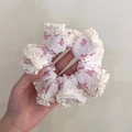 White lace hair scrunchie with pink bow patterns and ruffle edges held in hand - Q617-2 White Pink Bow Ruffle
