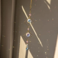 Hanging amethyst suncatcher with golden prisms creating rainbow light on a white wall - Amethyst Large Square Style