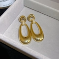 Detailed view of polished gold oval earrings with zircon inlay in a jewelry box - Oval Hollow Style / Gold