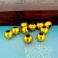 Dettaglio macro di perle a zucca dorate lucide per gioielli fai-da-te su panno blu - Perla liscia da 9 mm (foro da 4 mm)