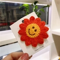 Handcrafted orange crochet flower hair clip with a yellow smiley face center on card - Orange Smiley Flower