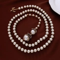 Detailed macro shot of vintage pearl necklace with eagle charm on dark red silk - Gold