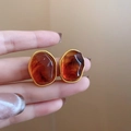 Close-up of elegant amber resin irregular earrings with twisted gold borders held by hand - 26# Silver Earring Post - Gold - Brown - Oval