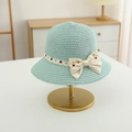 Detalle de sombrero de paja verde claro con elegante lazo de lunares en un soporte - Sombrero / Azul