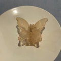 Detail of translucent butterfly hair claw with golden spring on a white ceramic plate - Orange