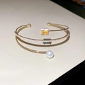 Detailansicht eines Goldarmreifs mit gelbem Edelstein, Pavé-Diamanten und einer weißen Perle - Gold-Quadratischer Gelber Diamant (HB4660)