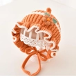 Detail of baby knitted bonnet with orange white stripes and 3D floral accent - 3M-2Y / Orange