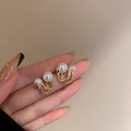 Detail of gold double-layered round pearl earrings held in hand with elegant style - C-Shaped Pearl Stud Earrings / Gold