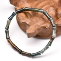 Macro detail of natural stone bamboo-shaped beads with deep green polished mineral texture - Bamboo Style Agate