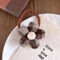 Detailed view of a brown checkered floral hair tie on a white ceramic plate and napkin - Plaid Pattern Hair Tie