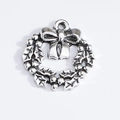 Detailed macro view of a silver Christmas wreath charm with holly leaves and bow knot - Christmas Wreath
