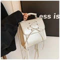 Close-up of cream PU leather handbag with decorative drawstring bow and silver hardware - White