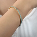 18k vergoldetes Tennisarmband mit hellblauen Zirkonia Steinen am Handgelenk einer Frau - Hellblau Zirkonia Goldfarbe