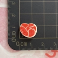 Vista detallada de dije de resina en forma de corazón de 1 cm sobre tapete de corte - Un Trozo de Carne