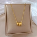 Detail view of interlocking titanium steel Roman numeral rings on a gold necklace - Gold