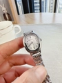 Close-up of a silver oval quartz watch with a metal strap held in a hand - Silver White Dial
