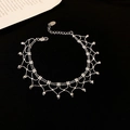 Detailansicht eines silbernen Spitzen-Armbands mit Perlenanhängern auf schwarzem Grund - Armband - Silber