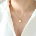 Minimalistische Goldkette mit poliertem Sechskantanhänger an Model auf weißem Strick - Achteckig Poliert / Gold